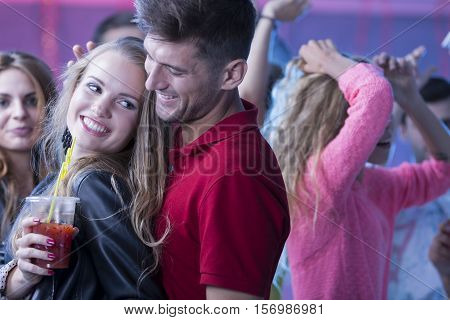 Young woman holding a drink dancing with a handsome man during nigth party