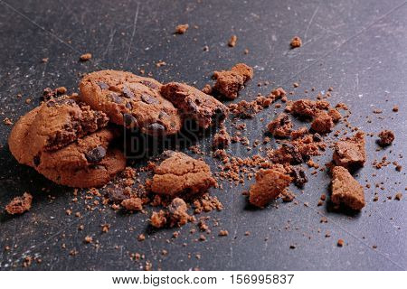 Tasty cookies with chocolate chips and crumbs on dark background