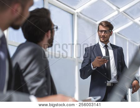 businessman with a smartphone standing in his ofiice
