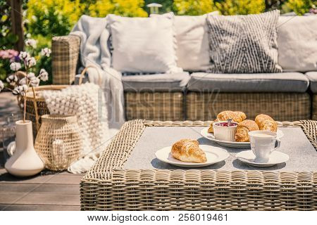 An Outdoor Wicker Table And A Sofa With Cushions. Croissants For Breakfast On A Patio On A Summer Mo