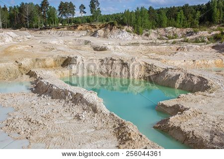 Kaolin clay quarry open pit at summer day with blue water