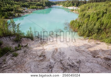 Kaolin clay quarry open pit at summer day with blue water