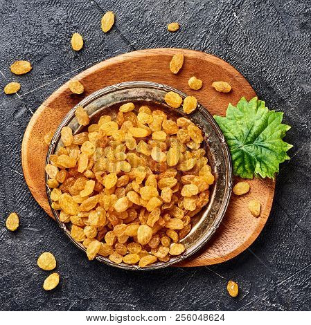 Yellow Raisins On Black Concrete Background. Top View Of Dried Grapes.