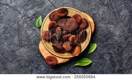 Brown Sun Dried Apricots On Black Table. Top View Of Dry Fruits With Copy Space.