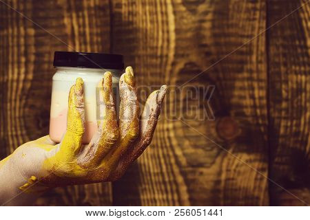 Female Hand Smeared In Golden Glister Holding Selective Focus Jar With Colorful Paint On Brown Vinta