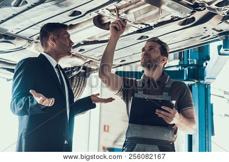 Auto Mechanic Showing Client Car Problem. Buisness Man In Black Suit Dont Understand Cause Of Breaka