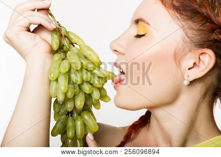 Beautiful Redhead Woman Licks Grapes. Concept Of Healthy Eating