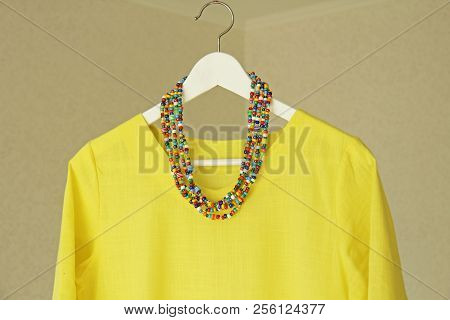 Bright Beads Of Murano Glass Hang On The Background Of A Yellow Summer Dress. Summer Jewelry, Summer