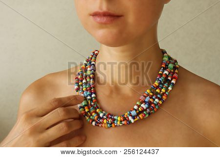 Bright Beads Of Murano Glass On A Young Girl. The Girl's Hand Touches The Beads
