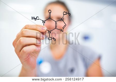 Young woman holding up a molecular model of nicotin