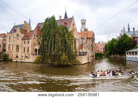 Bruges, Belgium-august 15, 2015-the Belfry Tower, The Medieval Houses And The People In Boat At The 