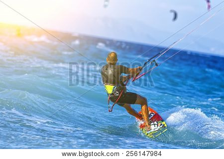 Man Kitesurfer Riding The Waves With Strong Winds. Bright Sunny Day.