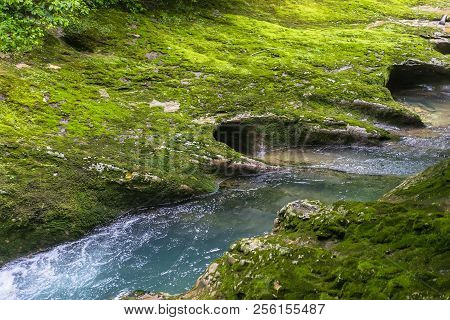 Small Mountain River Flowing Through The Green Forest In Stone Bed. Rapid Flow Over Rock Covered Wit