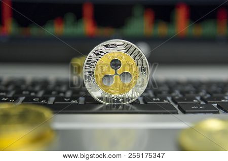Golden And Silver Ripple Coin With Gold Coins Lying Around On A Black Keyboard Of Silver Laptop And 