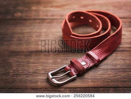 Girdle Of Red Leather. Fashionable Leather Belt On A Wooden Table.