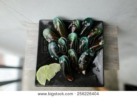 Black Ousters Near Lmon On Black Plate.