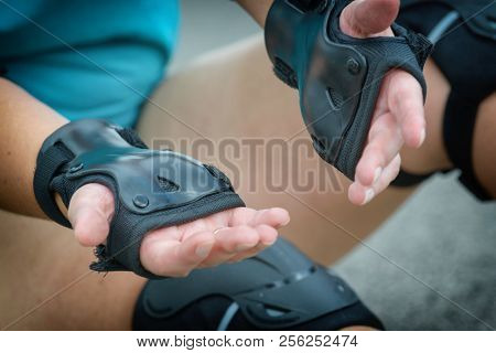 Woman rollerskater wearing wrist guards protector pads on her hand