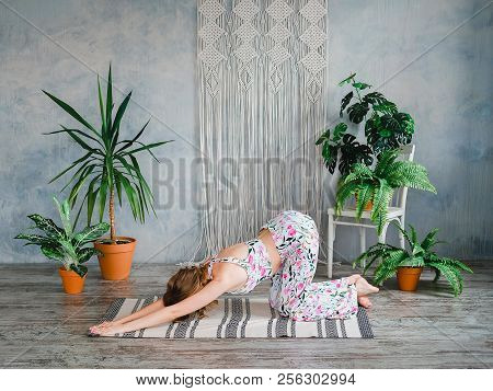 Young Woman Doing Puppy Pose In Boho Interrior. Yoga At Home Concept.