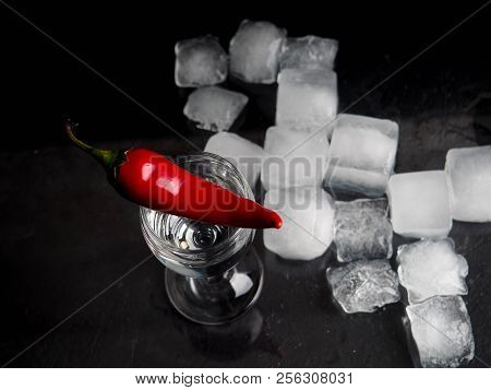A Shot Of Vodka, An Alcoholic Beverage, Next To Ice, Fire, Ice, Red Chili Pepper. The Concept Of Alc
