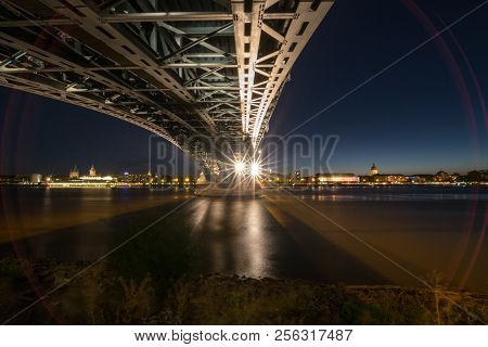 Picture With Red Lense Flare Of The German City Of Mainz With Theodor Heuss Bridge Seen From Wiesbad