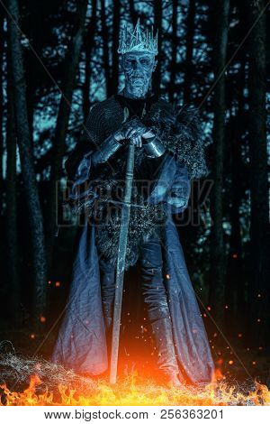 The king of the dead warriors in knightly armor stands in the night forest. Fantasy horror film. Halloween. Zombie.