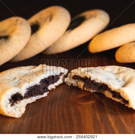 Chocolate Filled Cookies Cut In Half With Chocolate Cream And Cookies In The Back On Wooden Backgrou