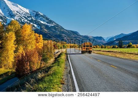 School bus on highway in Colorado Rocky Mountains at autumn, USA. Mount Sopris landscape.