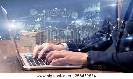 Businessman typing on laptop with linked reports charts grapghs around