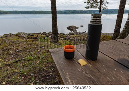 Coffeecup And A Thermos At A Table Near A Lake