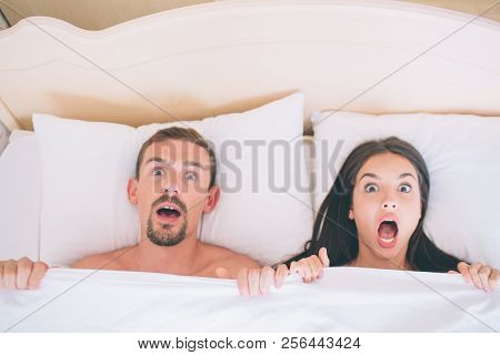 Sared And Terified Man And Woman Are Lying In Bed. They Covered With White Blanket. People Hold It W