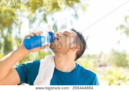 Young Male Athlete Drinking Water From Waterbottle After Workout In Park