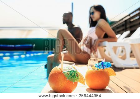 The African Man And Woman As Friends Playing And Relaxing In A Swimming Pool During Summer Holidays.