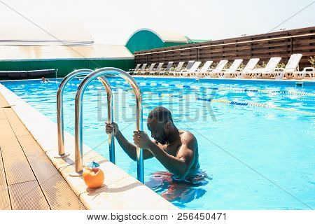 The Portrait Of Happy Smiling Beautiful Man At The Swimming Pool. Female Caucasian Model At Blue Wat