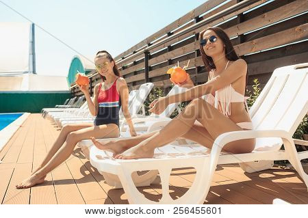 Happy Smiling Two Girls As Friends Playing And Relaxing In A Swimming Pool During Summer Holidays. P