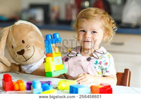 Adorable Toddler Girl With Favorite Plush Bunny Playing With Educational Toys In Nursery. Happy Heal