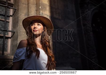 Outdoor Portrait Of Young Tourist Woman Walking On Old City Street. Girl Looking At Ancient Atchitec