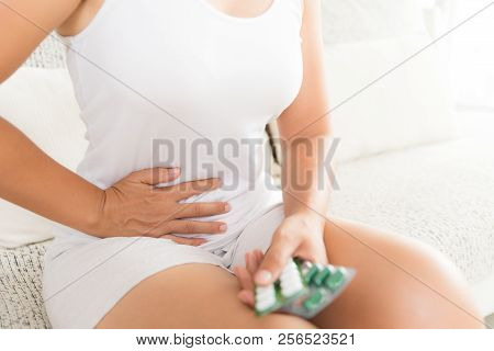 Young Woman Having Painful Stomachache Sitting On Sofa At Home. Chronic Gastritis. Abdomen Bloating 