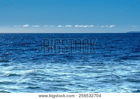Thin White Cloud Above Distant Horizon Blue Sky And Sea Tones Blending With Sun Sparkles On Water Id