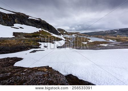 Typical norwegian landscape with snowy mountains and clear lake near the famous Aurlandsvegen (Bjorgavegen), mountain road, Aurland, Norway.