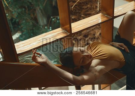 Preety Woman Relaxing While Lying On A Wooden Stair Railing Near