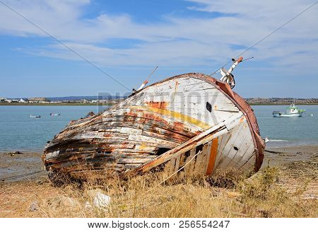 Ayamonte, Spain - June 11, 2017 - Old Wooden Fishing Boat Ruin On The Riverbank With Views Across Th