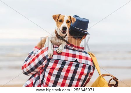 Fahionable Male Host Of Beauitiful Dog, Carries It On Hands, Come To See At Sunset On Seashore, Spen