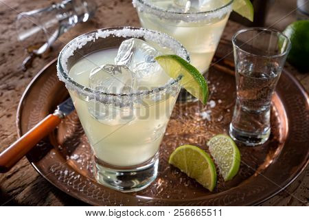 Delicious Tequila And Lime Margaritas On A Copper Charger With Coarse Salt Rimmer.