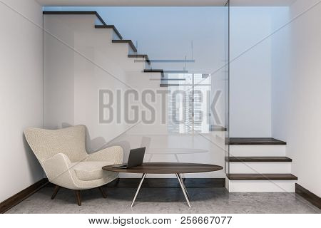 White Comfortable Armchair Standing Near A Coffee Table With A Laptop In A Hotel Lobby. A Staircase 