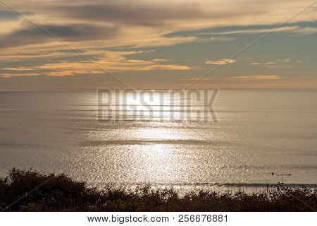 Shimmering Ocean Silver Sun Lit Sunset View With Blue Sky And Clouds In The Background