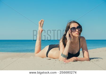 Beautiful Young Woman In Swimsuit At Sand Sea Beach Lying Under Sun Rays Tanning, Toned Image