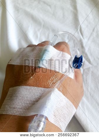 Patient Hand With The Tube Of Normal Saline Infusion On White Cloth Background