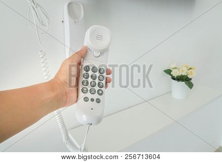 Close Up Woman Hold Handset With Numeric Keypad Of Wall Landline Phone By Left Hand For Calling
