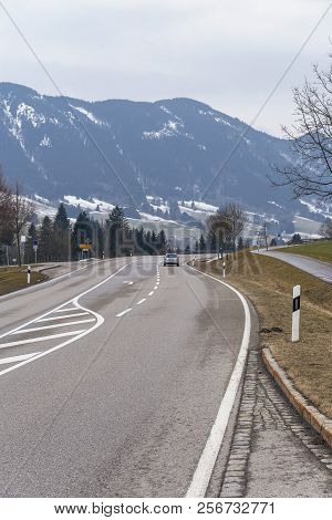 A Picturesque Asphalt Road In The Background Of The Mountains Near The German City Of Fuessen