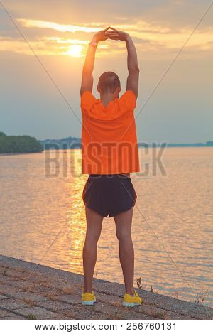 Young Man Stretching On A Fence After Jogging / Excercising.